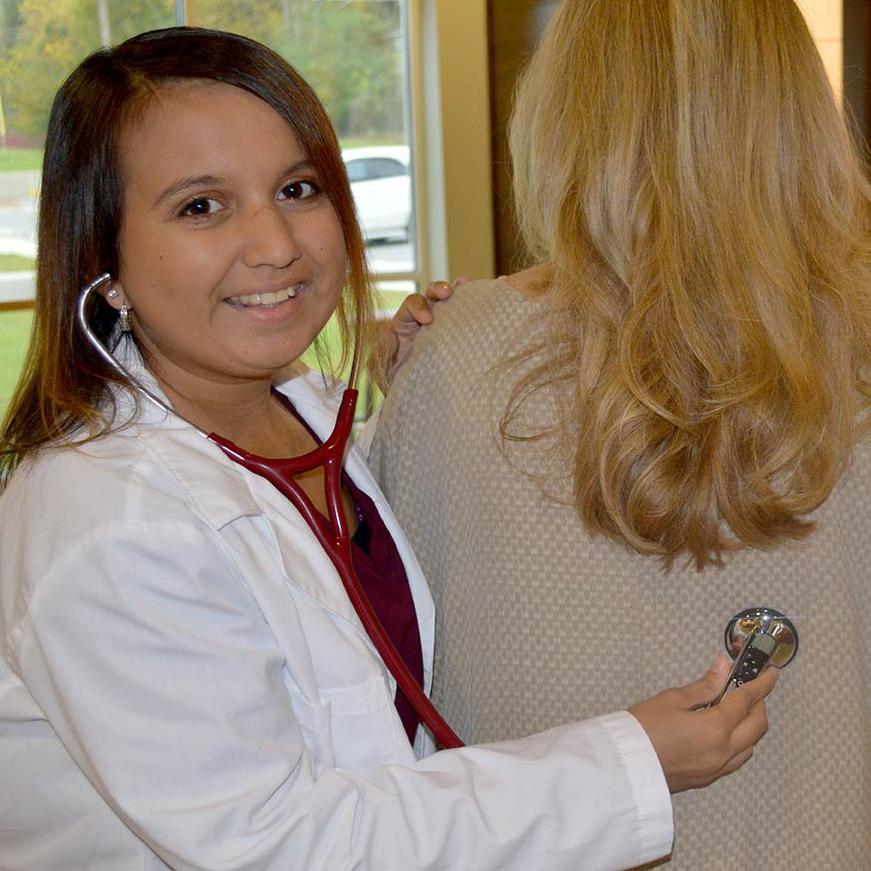 A health sciences student wearing a 听力 aid using a stethoscope  